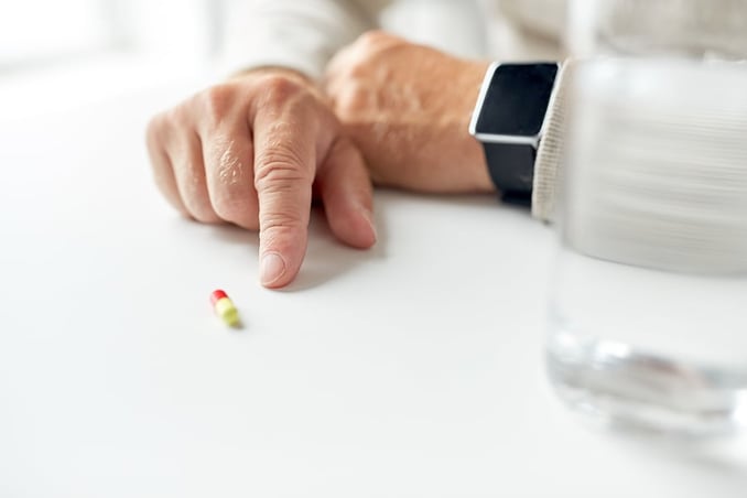 elderly patient wearing a smart watch pointing to medication inside a senior living facility