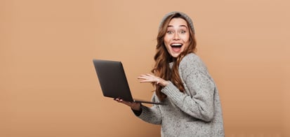 female smiling while holding a laptop